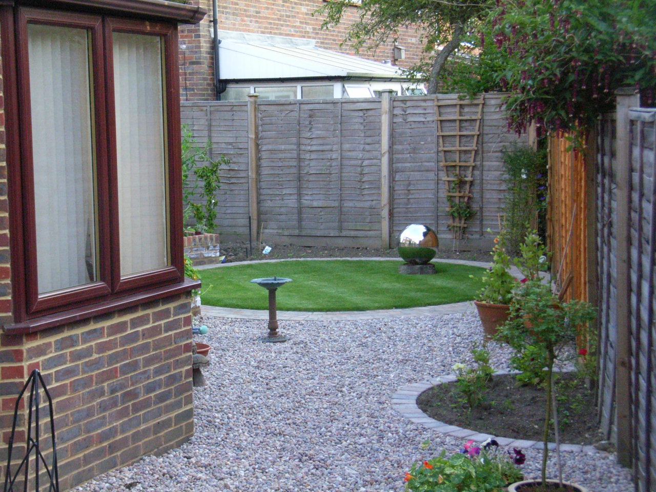 A small circular lawn and semi-circular beds, combined with Caledonian pebbles make this low maintenance garden stylish.