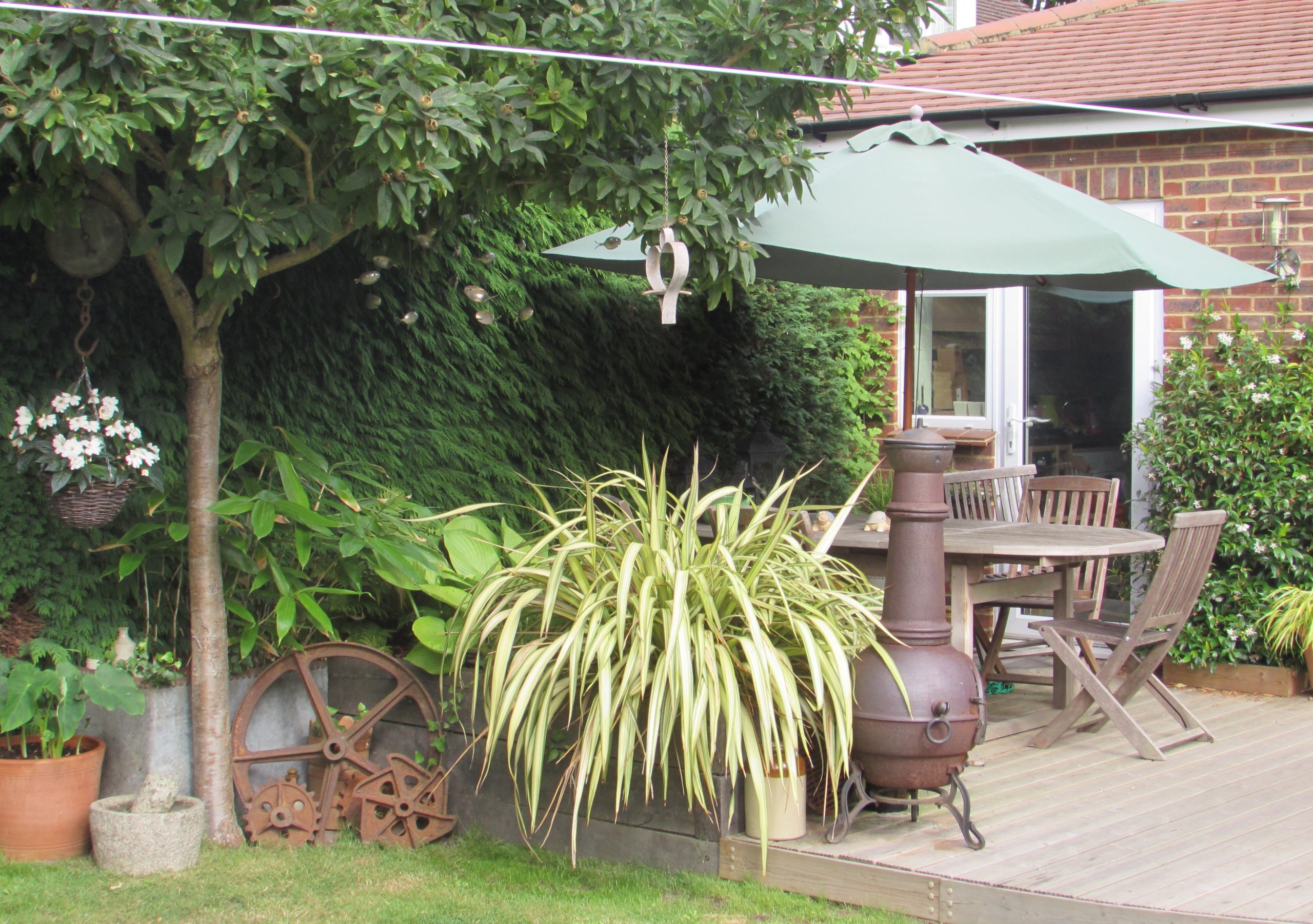 Any old iron. The vintage rusty metal, oak sleepers, lush foliage and curved decking make for a laid-back entertaining corner, perfect for unwinding